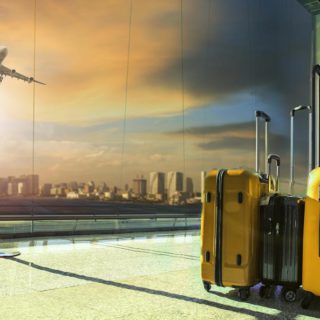 Dwie walizki w poczekalni na lotnisku na tle startującego samolotu
