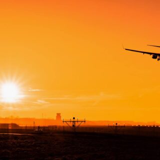 Sylwetka samolotu lądującego o zachodzie słońca na lotnisku Kraków Balice