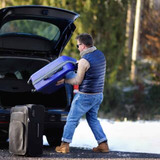 Mężczyzna pakuje bagaże do samochodu przed wyjazdem na urlop