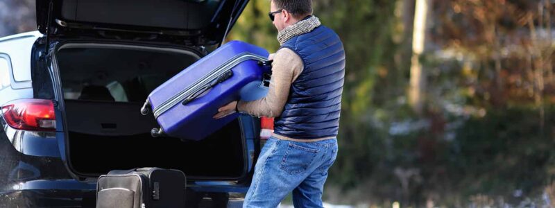 Mężczyzna pakuje bagaże do samochodu przed wyjazdem na urlop